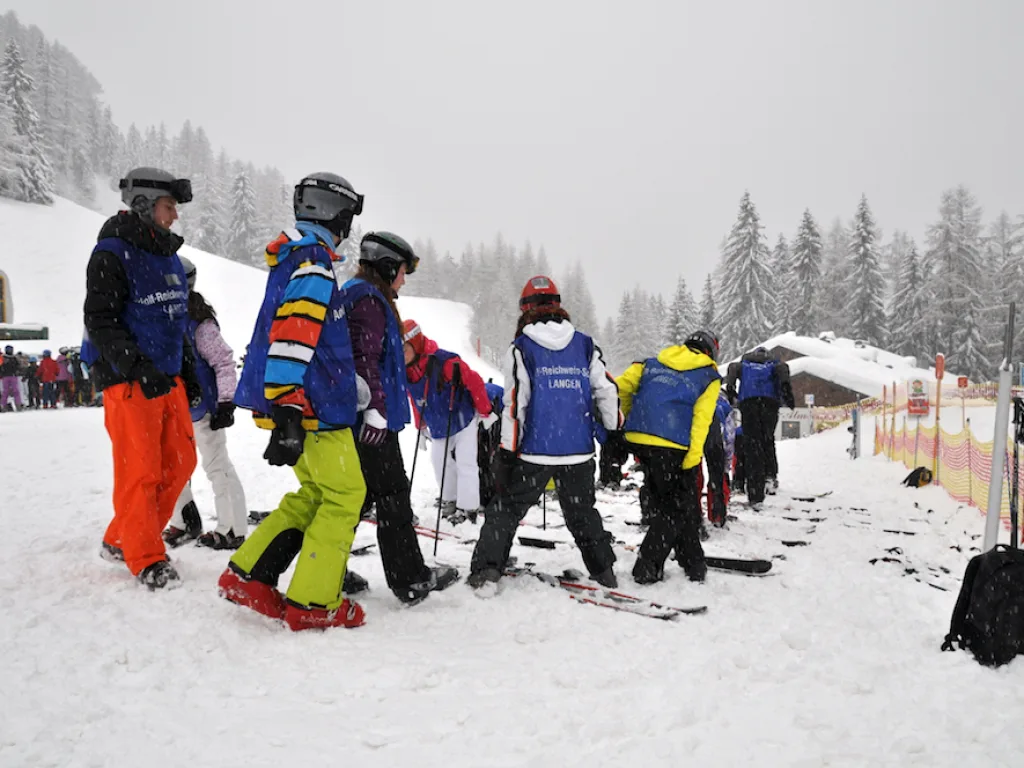 Jugendliche stehen mit Skiern vor der Hütte.